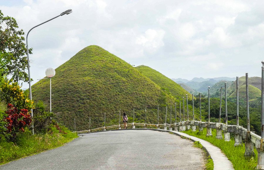A Chinese girl with one of the Chocolate Hills in the background
